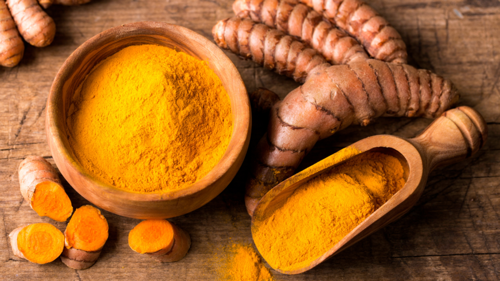 Racines de curcuma frais et poudre de curcuma biologique dans un bol en bois rustique